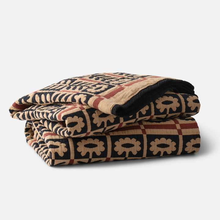 Folded Stillwater Quilt showing mirrored floral jacquard weave and bold color-blocking on white background