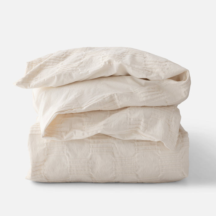Folded stack view of Woven Tally Duvet Cover showcasing woven stitch texture in natural color on white background