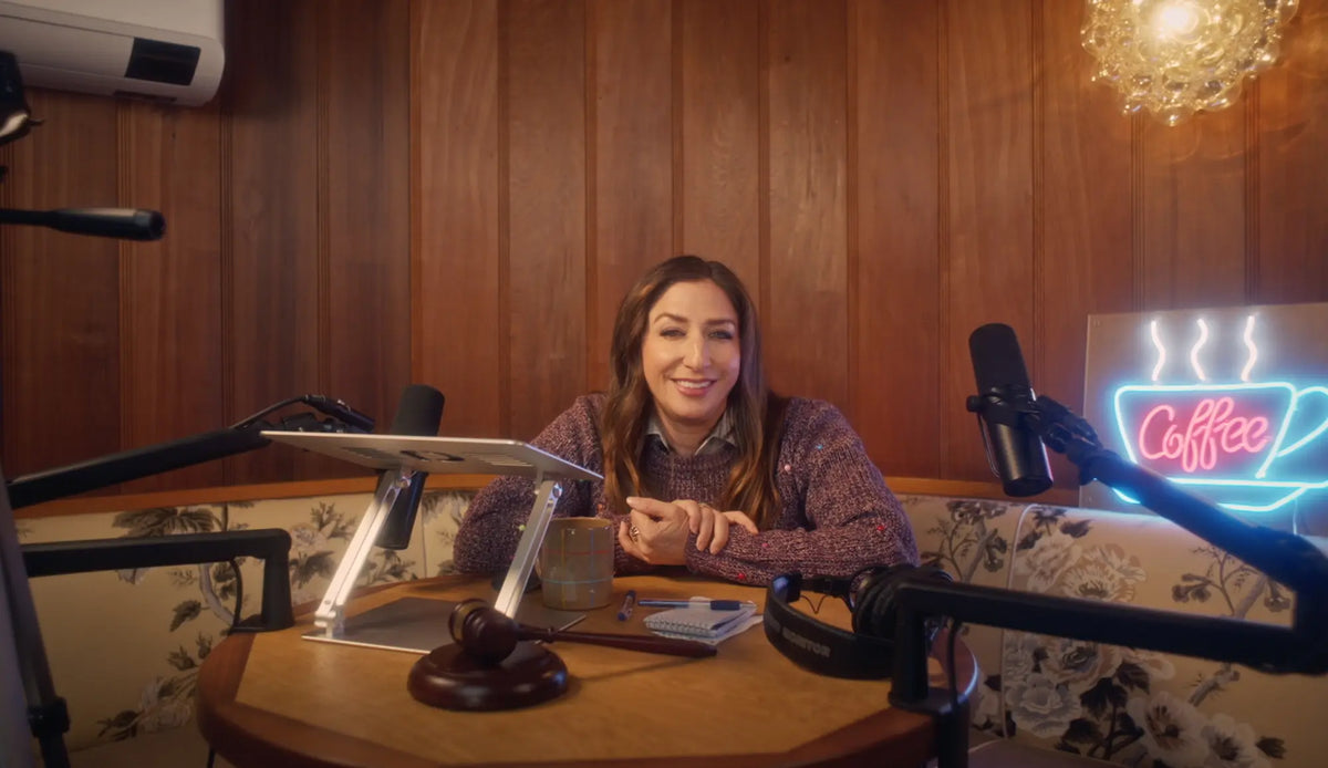 headshot of Chelsea Peretti sitting at table with microphone