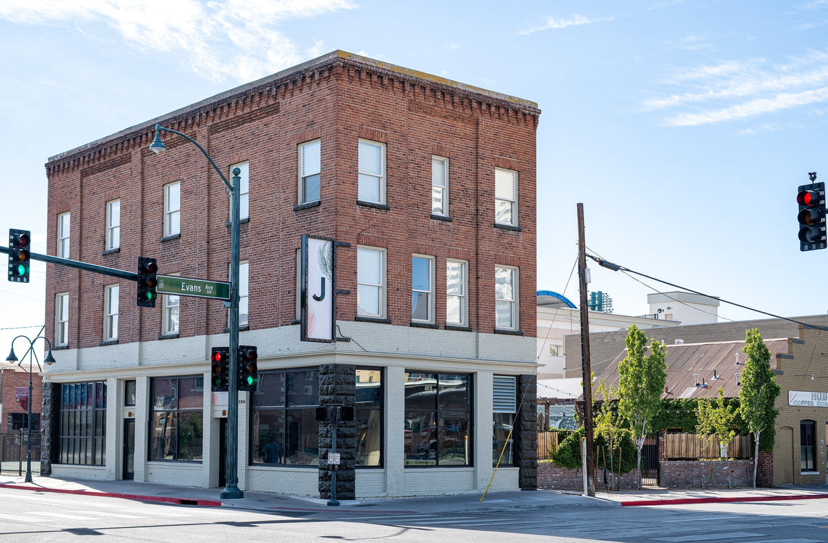Corner view of the three-story red brick Jesse Hotel and Bar at Evans Avenue in downtown Reno showing ground-floor windows and a vertical J sign