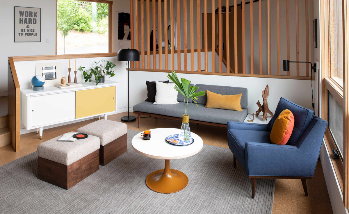 Living room with gray sofa and blue armchair, mustard pillows, midcentury coffee table, framed art reading Work Hard