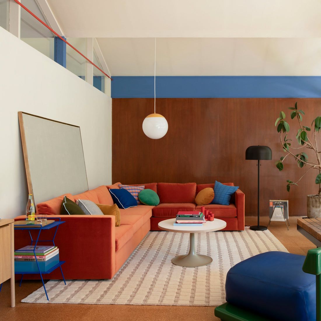 Mid-century living room with rust-orange sectional, colorful pillows, white globe pendant and black floor lamp
