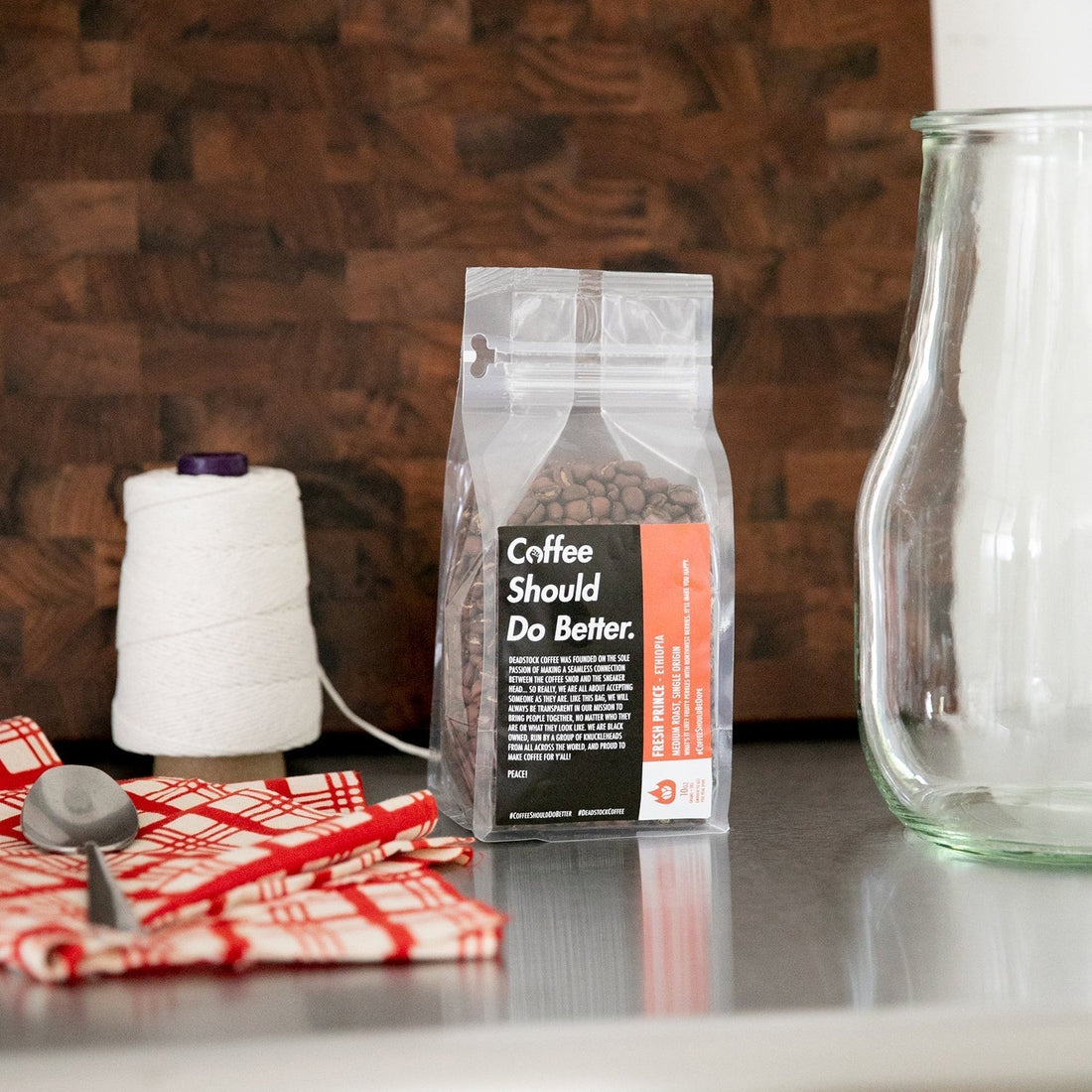 Front view of a clear resealable bag of whole-bean coffee labeled ‘Coffee Should Do Better’ on a kitchen counter