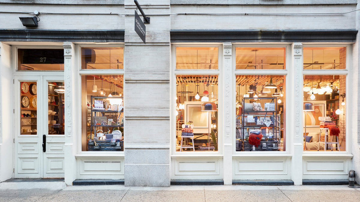 Exterior of Schoolhouse New York storefront with warm-lit window displays of light fixtures, shelving, and homewares in Tribeca