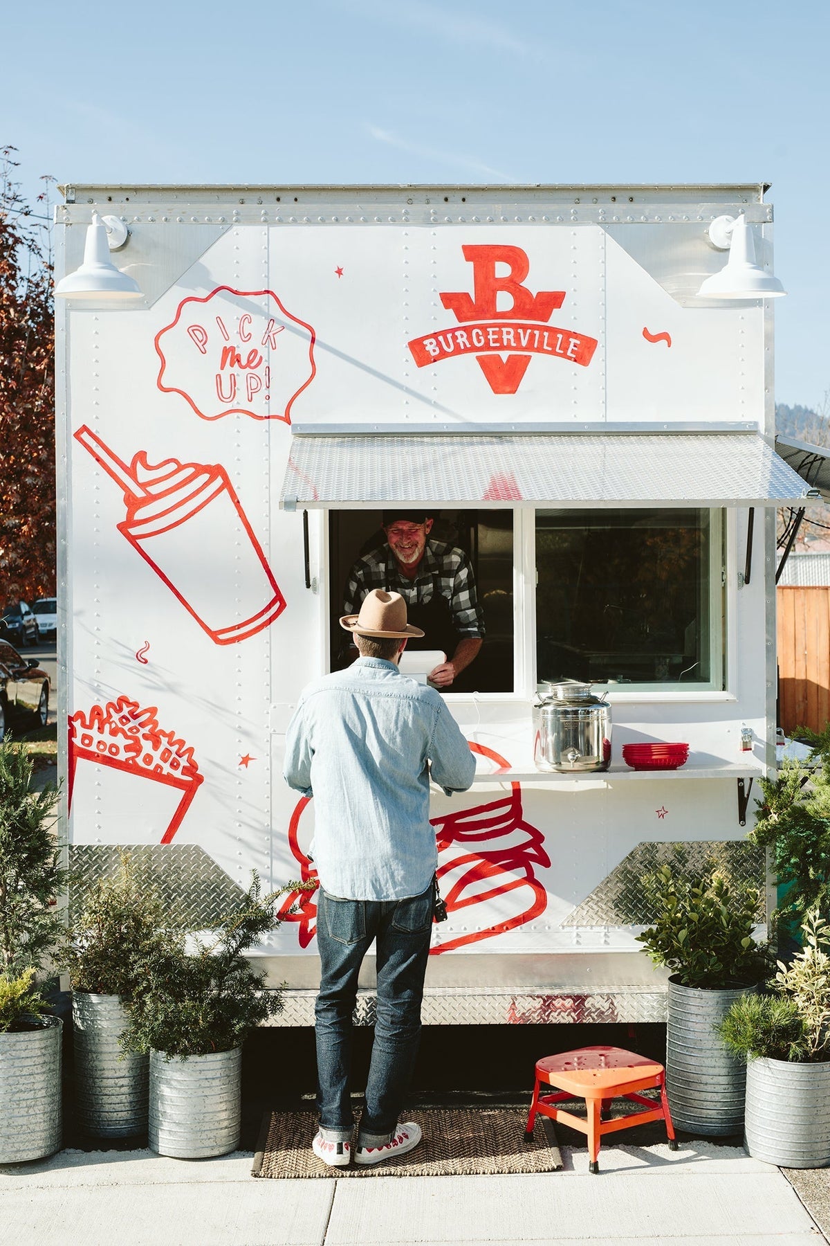 Customer picking up an order at a food truck with a red Burgerville logo and “Pick me up!” graphic