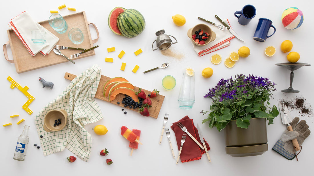 Flat lay of summer tableware and fruit arranged for casual entertaining on white background