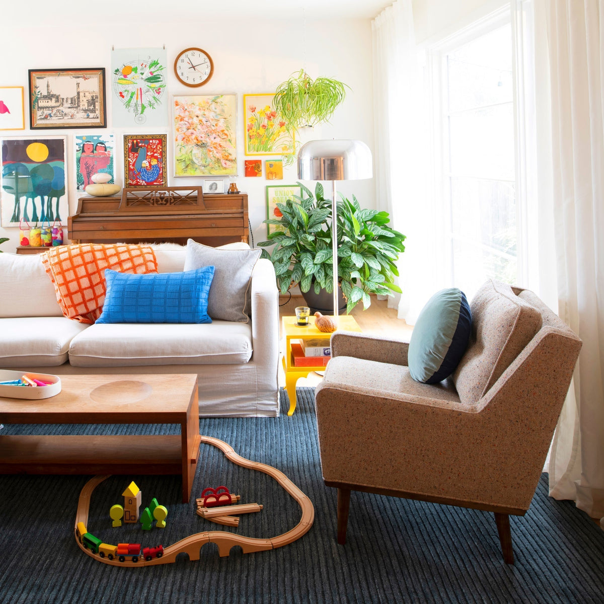 Family relaxing in a sunlit, joyfully styled living room with warm wood accents, pendant lights, a wooden coffee table, and indoor plants