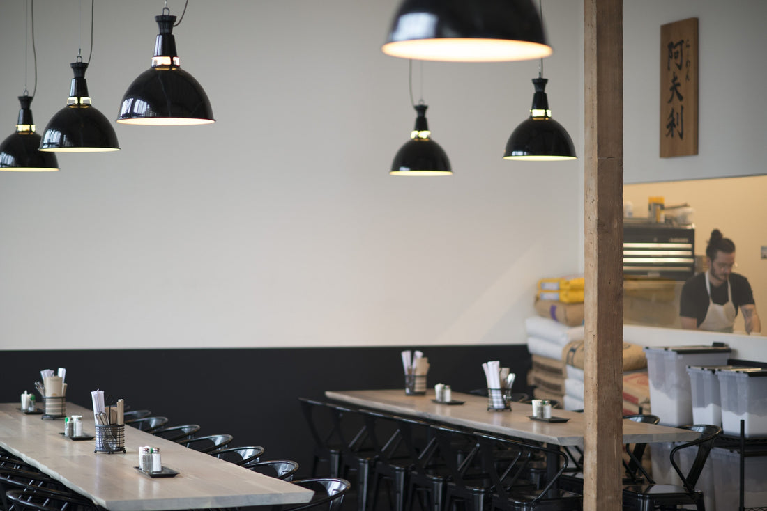 Communal wooden tables and black pendant lights in Afuri Ramen interior with a chef working behind the counter