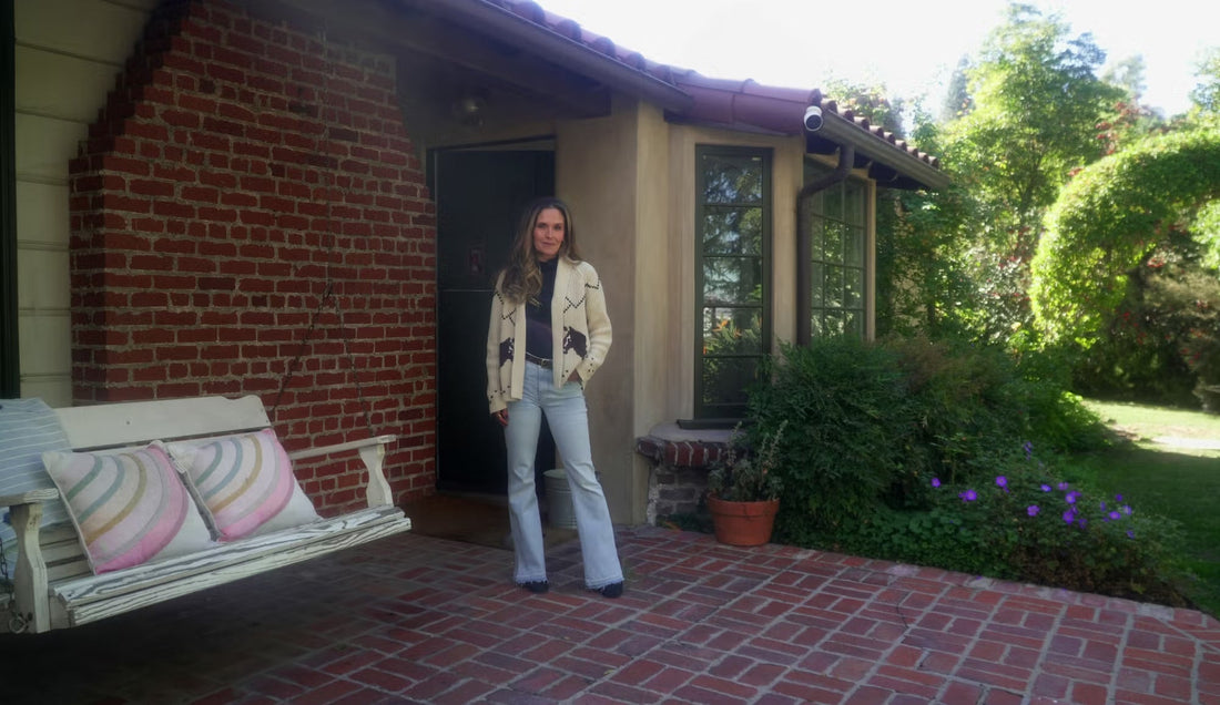 Woman in blue jeans and white cardigan in front of brick entry way