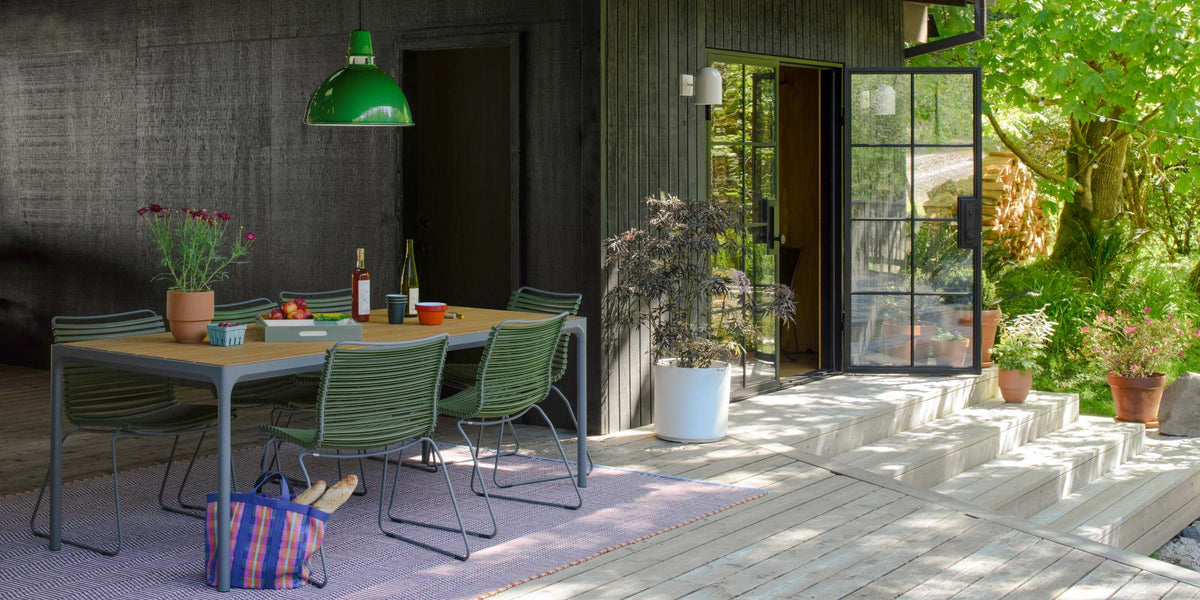 Summer outdoor dining table with green patio chairs