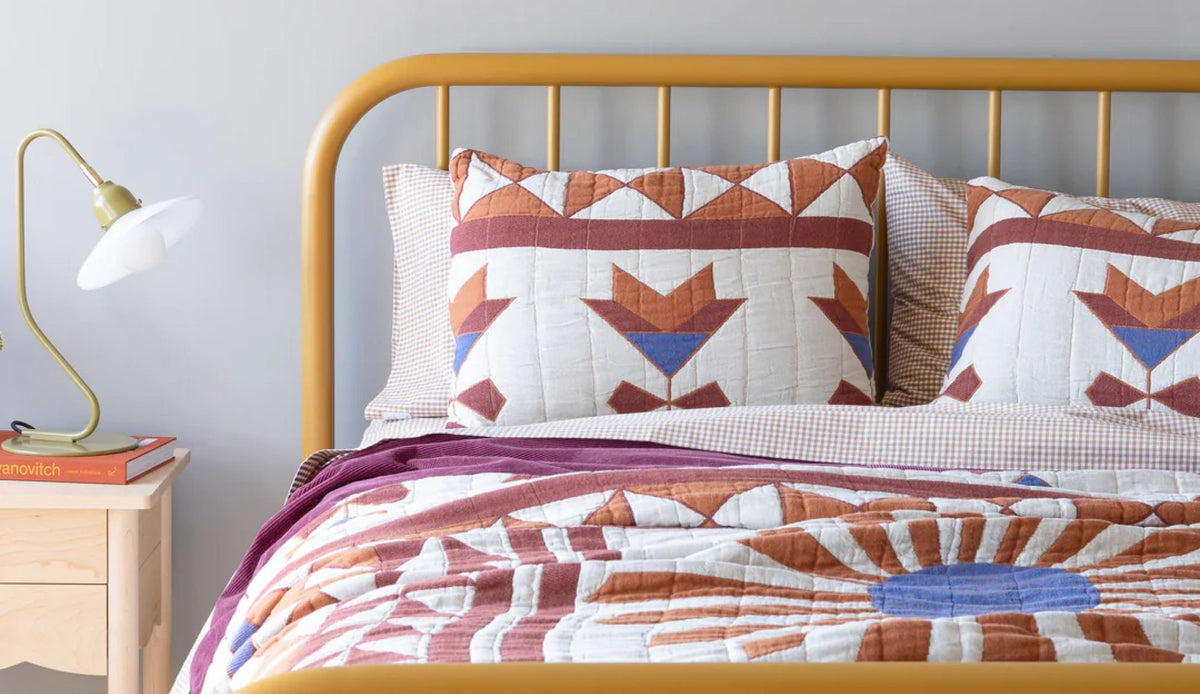 Colorful bedding on a yellow bedframe.