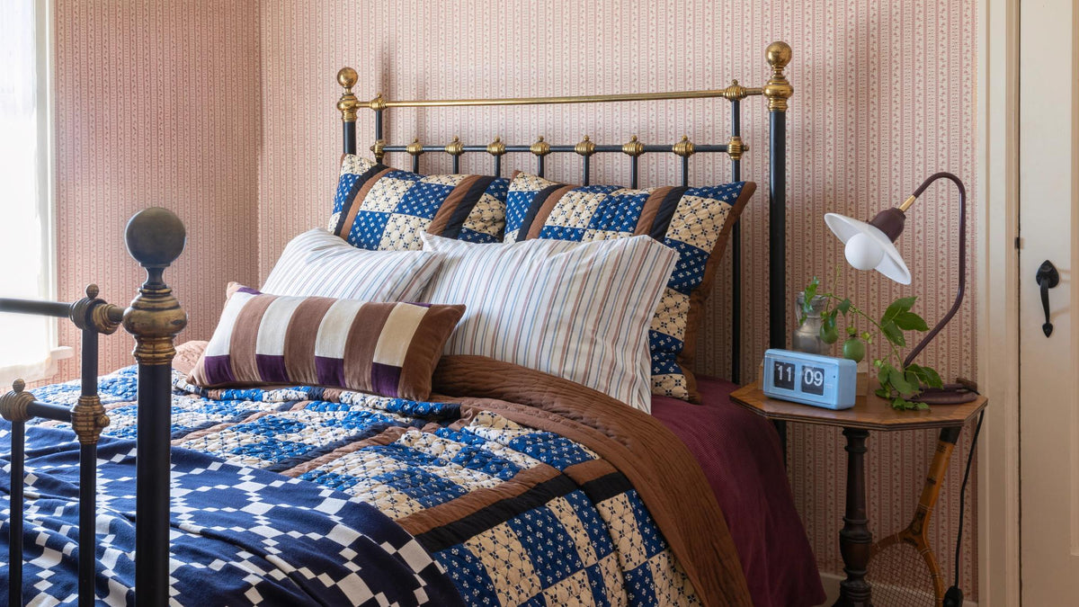 Cozy bed in wallpapered room.