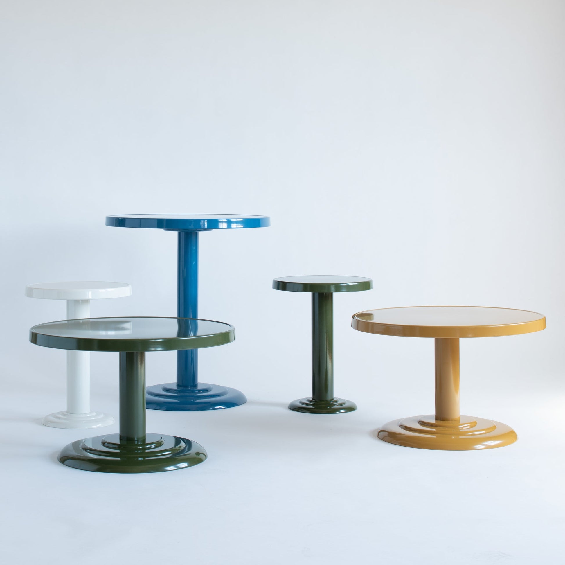Front view of Owen Bistro Tables in blue, white, olive, mustard showing glossy powder-coated steel tops on pedestal bases