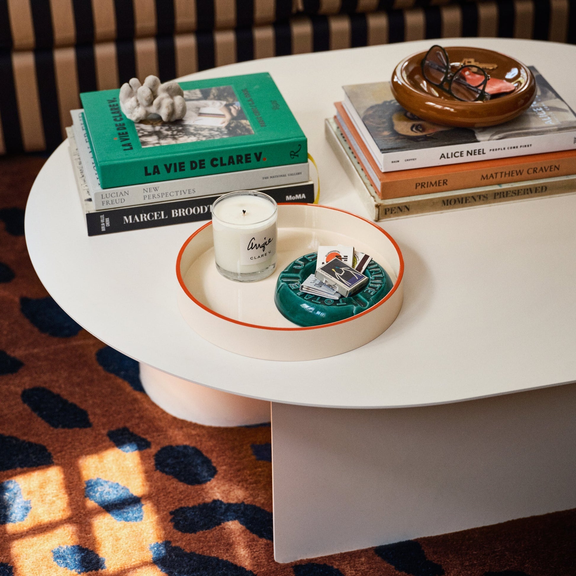 Angled top view of Yves cast metal catch all showing raisin gloss finish and shallow round shape on a white coffee table