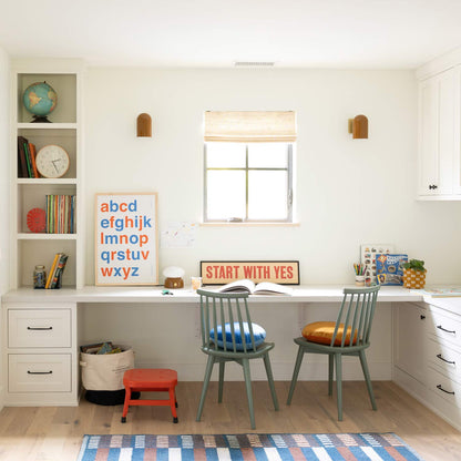 Two amber Allegheny wall sconces flanking a window above a built-in study desk with a START WITH YES sign