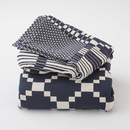 Folded Winter and Summer Cotton Coverlet showing navy and white woven geometric and striped patterns on white background