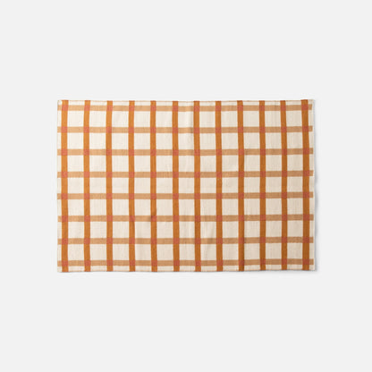Overhead view of Plaid Wool Reversible Rug showcasing orange and cream high-contrast plaid, handwoven natural-dyed wool on white background