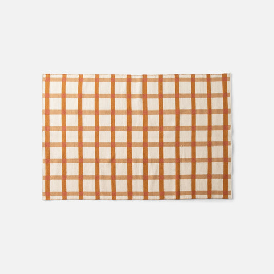 Overhead view of Plaid Wool Reversible Rug showcasing orange and cream high-contrast plaid, handwoven natural-dyed wool on white background