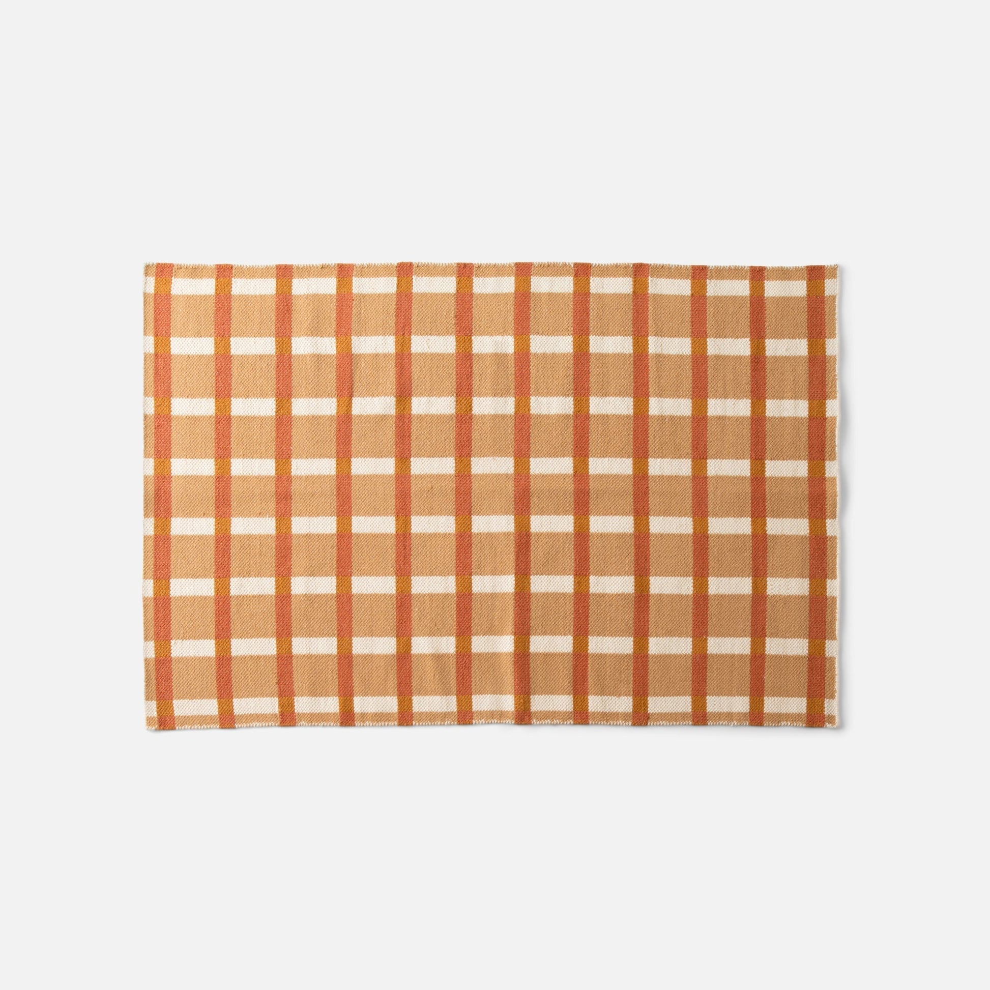 Top edge of Plaid Wool Reversible Rug showing handwoven orange, cream, and rust plaid wool on white background