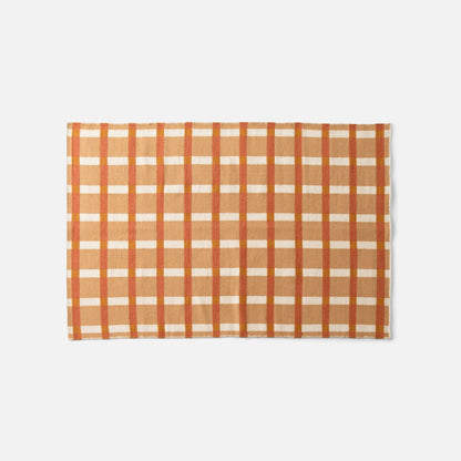 Top edge of Plaid Wool Reversible Rug showing handwoven orange, cream, and rust plaid wool on white background