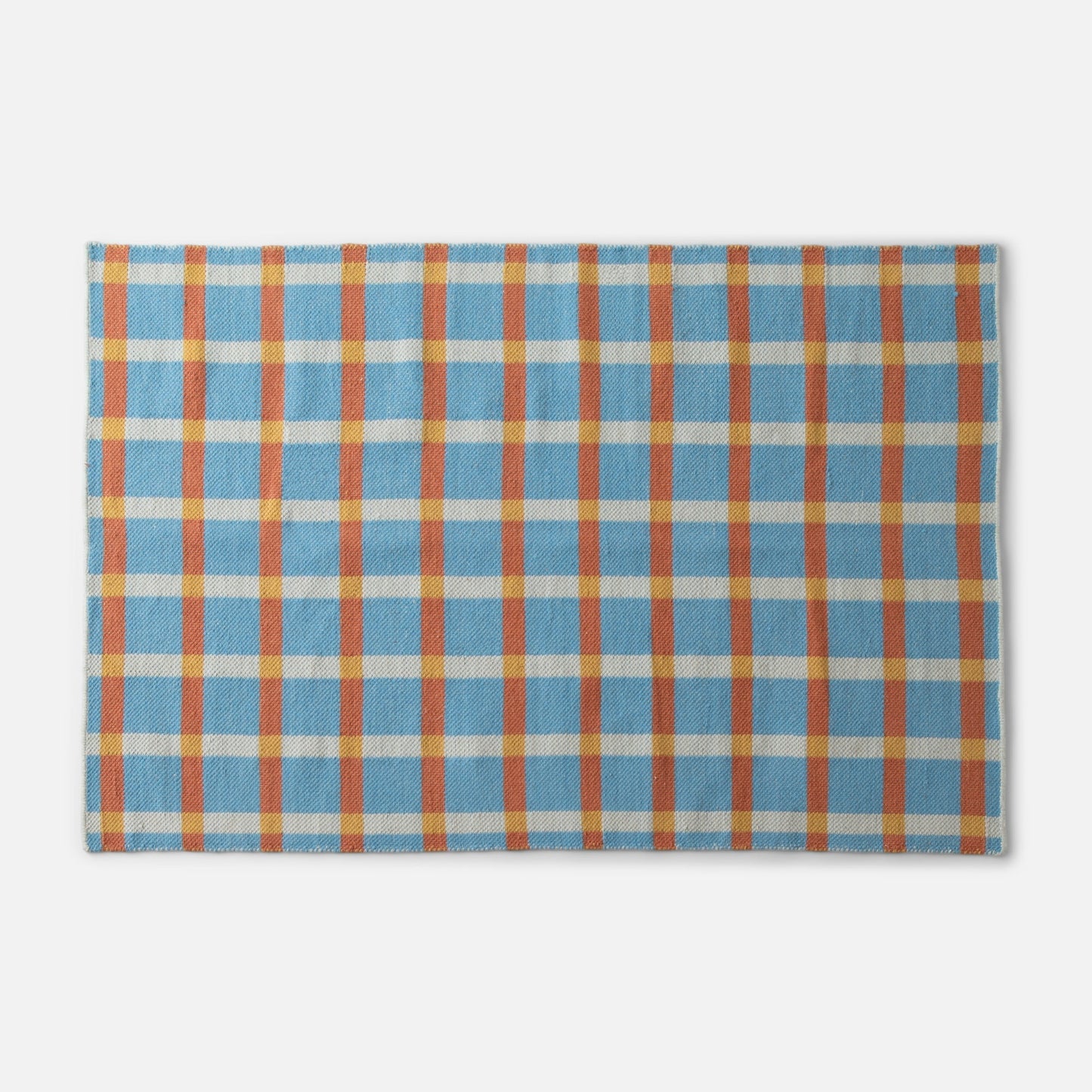 Top-edge close-up of Plaid Wool Reversible Rug showing blue, orange and yellow plaid handwoven wool texture on white