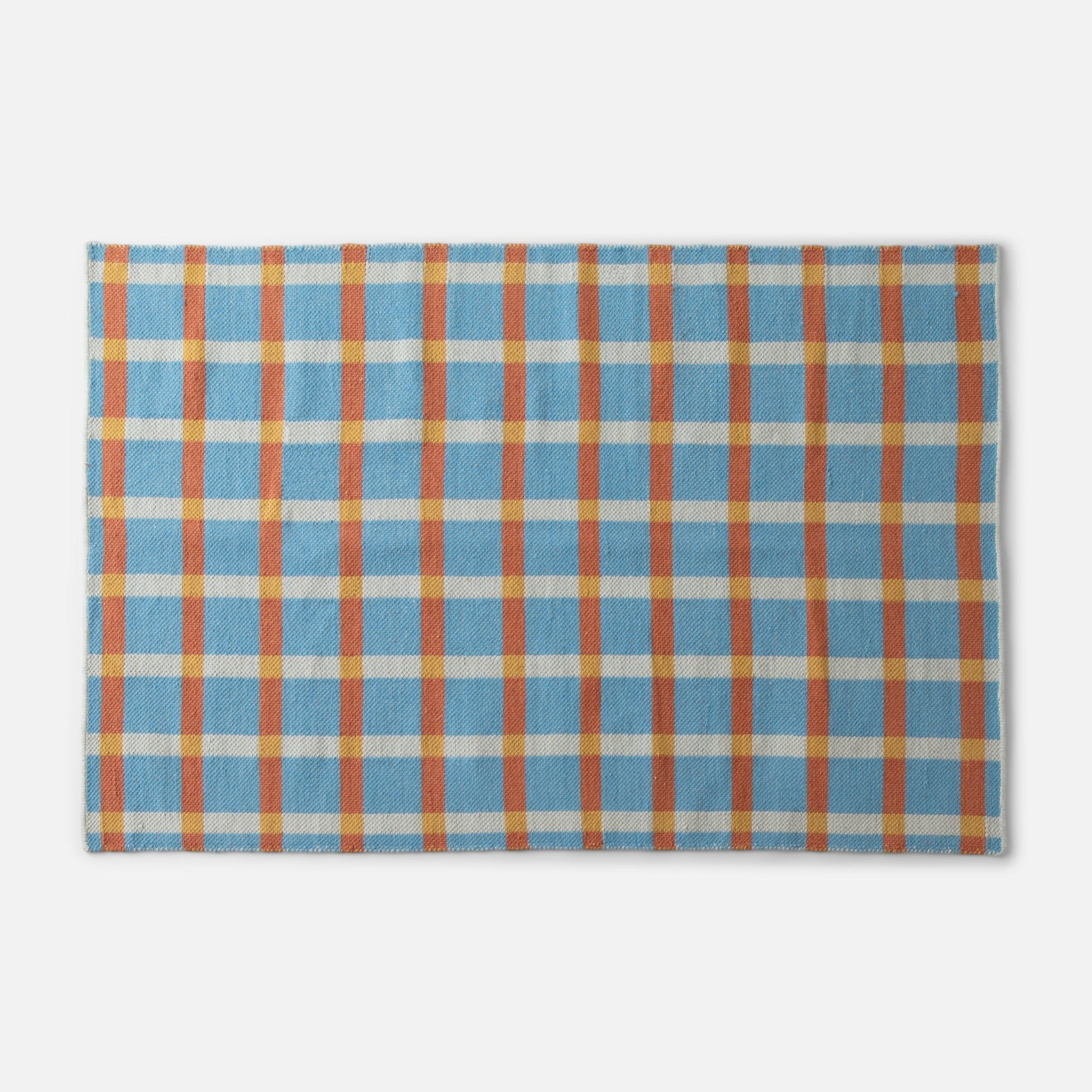 Top-edge close-up of Plaid Wool Reversible Rug showing blue, orange and yellow plaid handwoven wool texture on white
