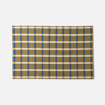 Top-down view of Plaid Wool Reversible Rug showing olive plaid with blue stripes, white grid and orange accents on white background