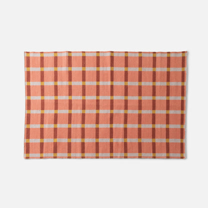 Top view of Plaid Wool Reversible Rug showing peach and rust high-contrast plaid handwoven wool on white background