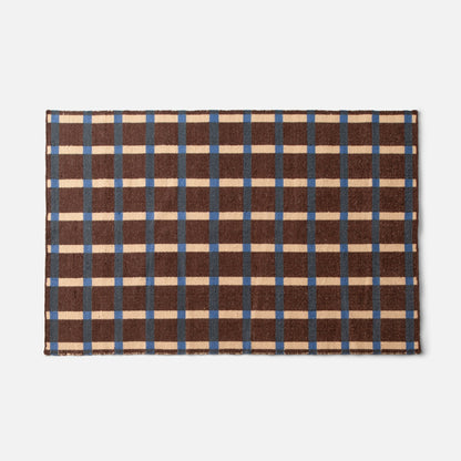 Top-down view of Plaid Wool Reversible Rug showing brown, cream, and blue plaid and woven wool texture on white background