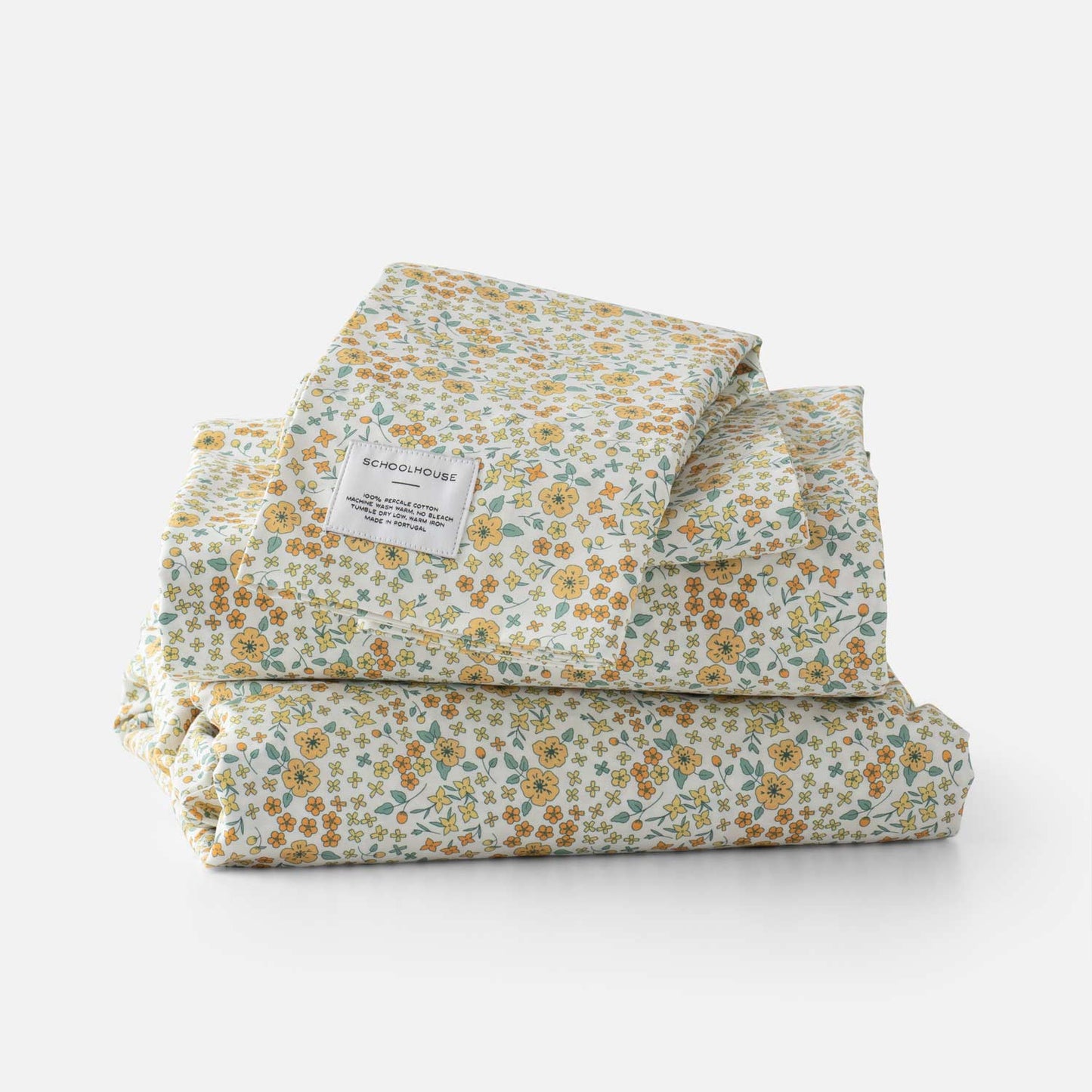 Front view of folded Wallowa Floral Percale sheet set showing yellow and green floral print and Schoolhouse label on white background