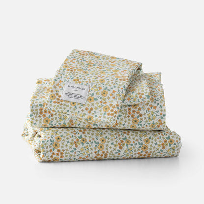 Front view of folded Wallowa Floral Percale sheet set showing yellow and green floral print and Schoolhouse label on white background