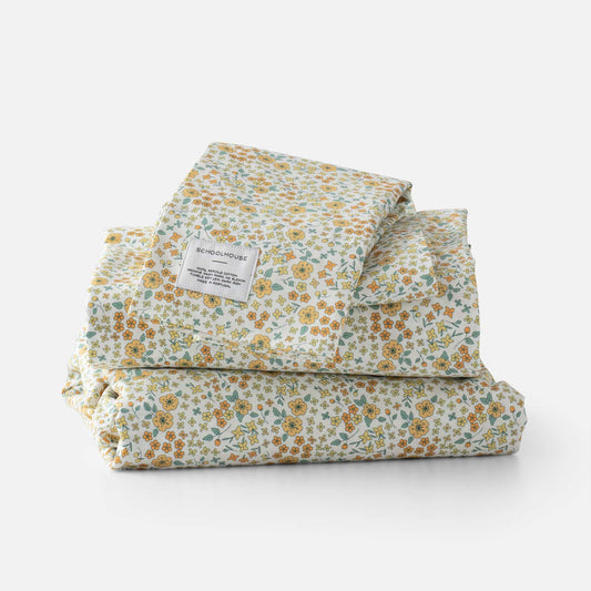 Front view of folded Wallowa Floral Percale sheet set showing yellow and green floral print and Schoolhouse label on white background
