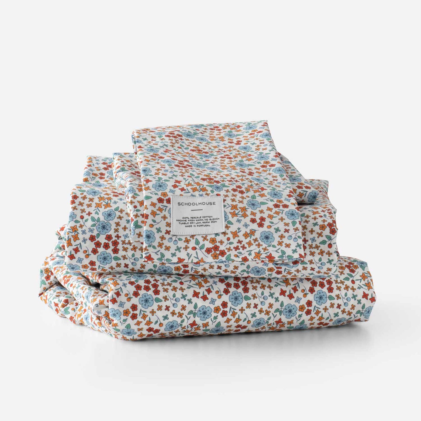 Stacked Wallowa Floral Percale sheet set showcasing multicolor floral print and Schoolhouse label on white background