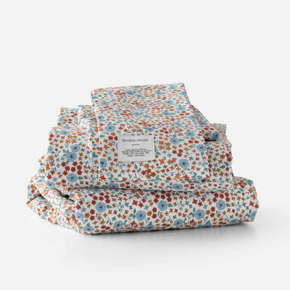 Stacked Wallowa Floral Percale sheet set showcasing multicolor floral print and Schoolhouse label on white background