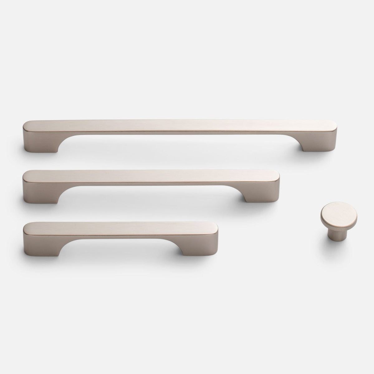 Front view of Roland Knob showcasing its round solid brass design alongside matching cabinet pulls on a white background