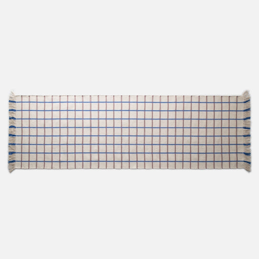 Top-down view of Cotton Grid flatweave rug showcasing blue and brown grid pattern and fringed ends on white background