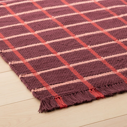 Angled close-up of Cotton Grid Flatweave Rug showing large grid pattern, flatwoven texture, and fringed edge on light wood floor