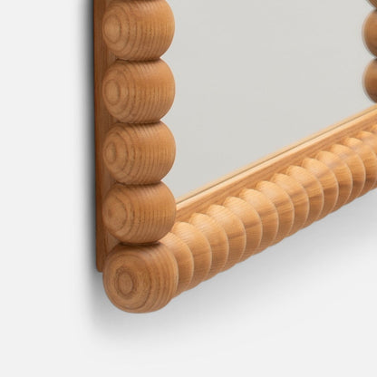 Close-up corner of Bobbin Mirror showing carved wooden bobbin frame detail on light gray background