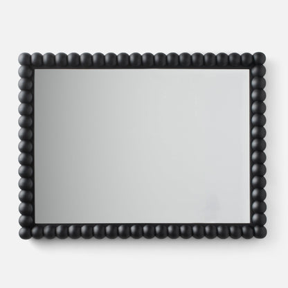 Close-up of Bobbin Mirror showcasing black beaded wooden frame on a white background