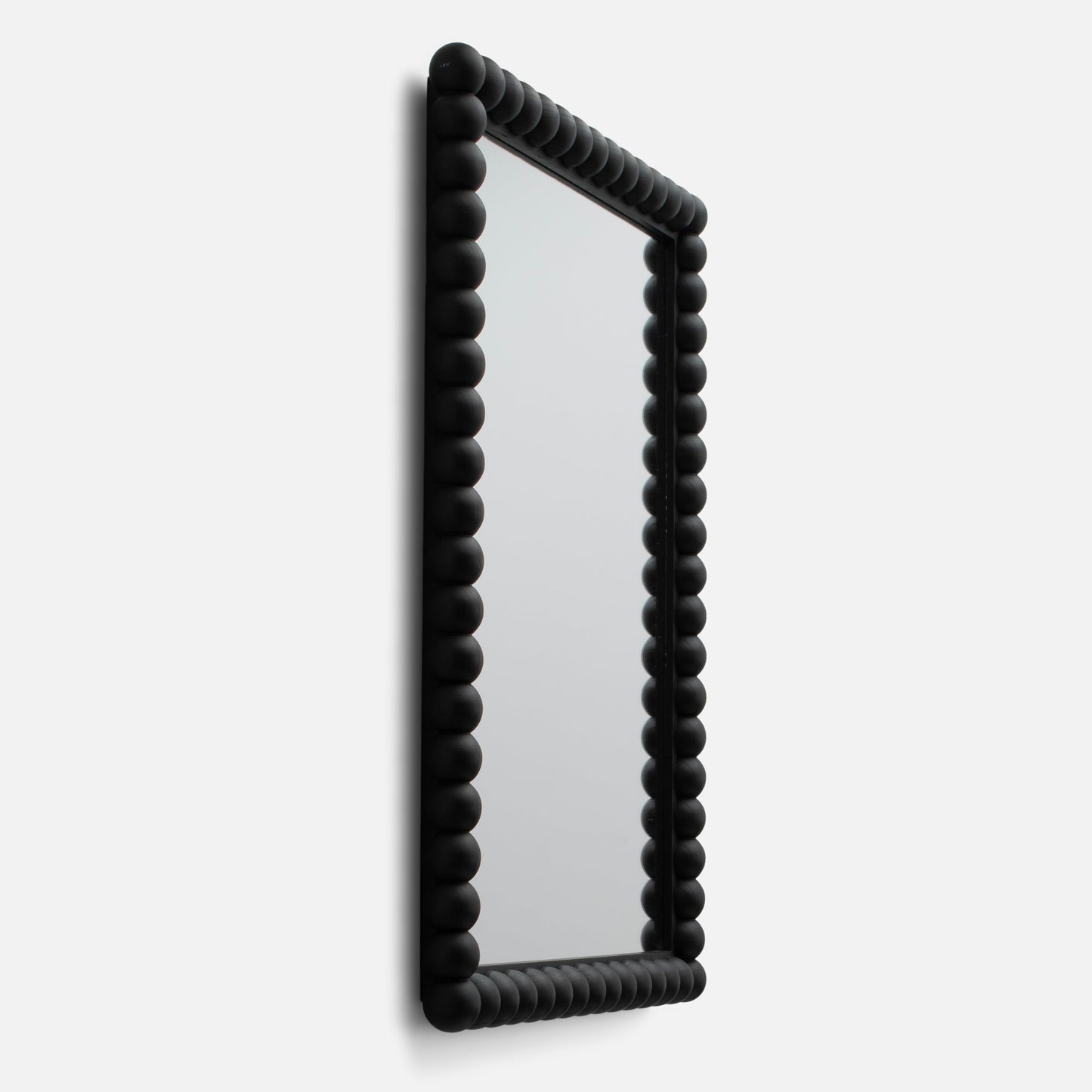 Angled side view of Bobbin mirror showing matte black beaded frame detail against a white background