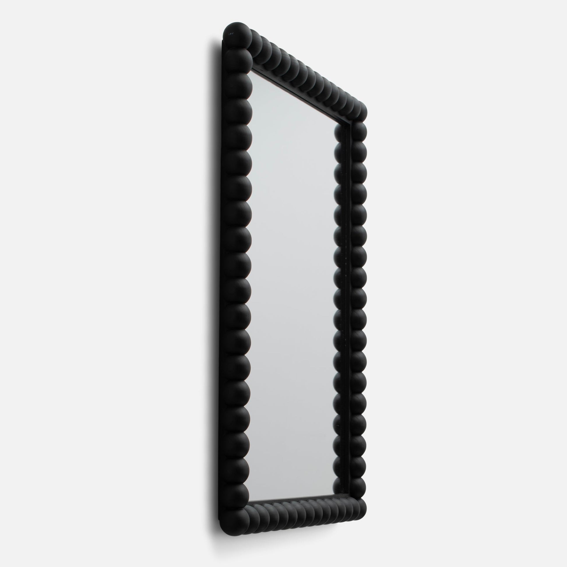 Angled side view of Bobbin mirror showing matte black beaded frame detail against a white background