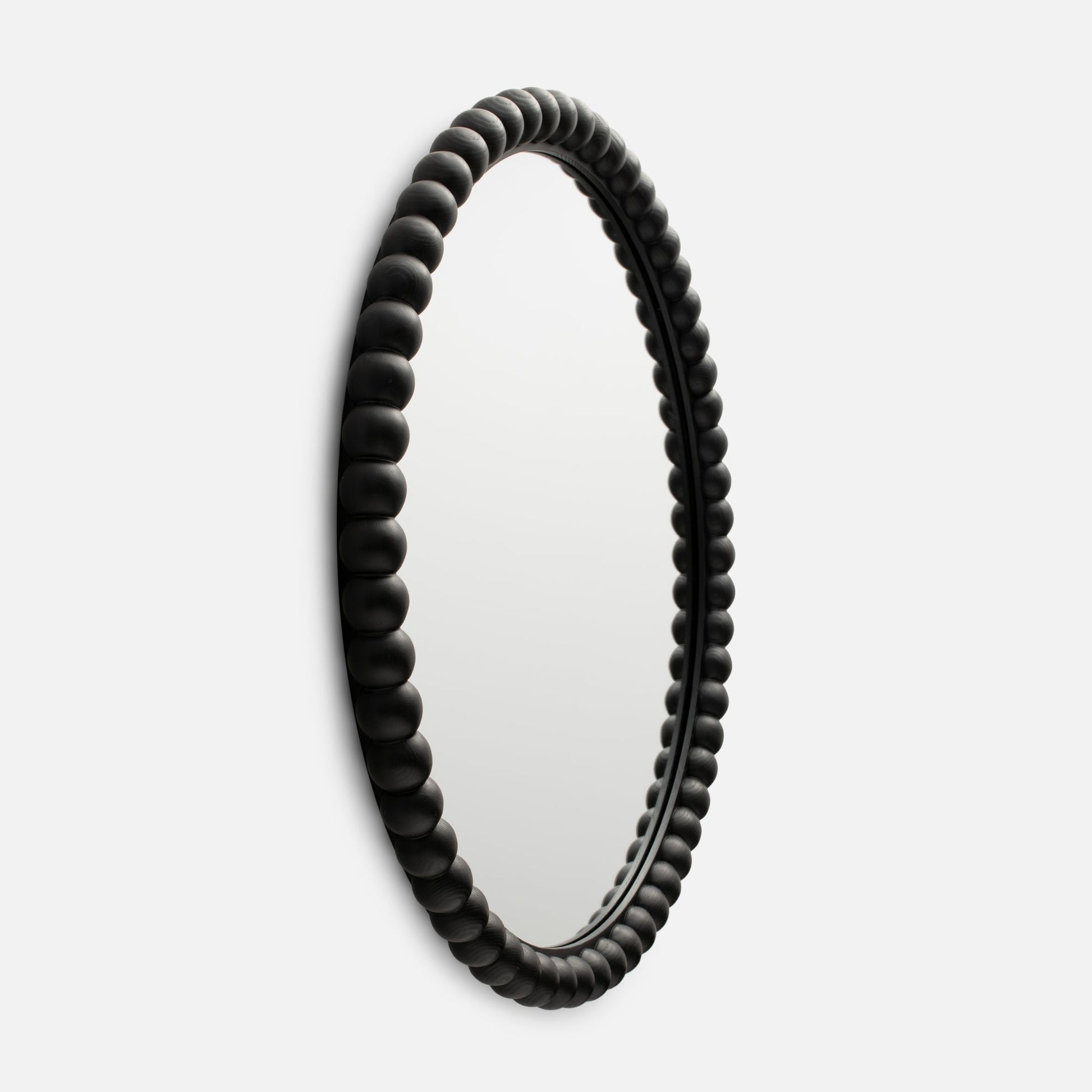 Close-up side view of Bobbin Mirror showcasing its black beaded wooden frame against a white background