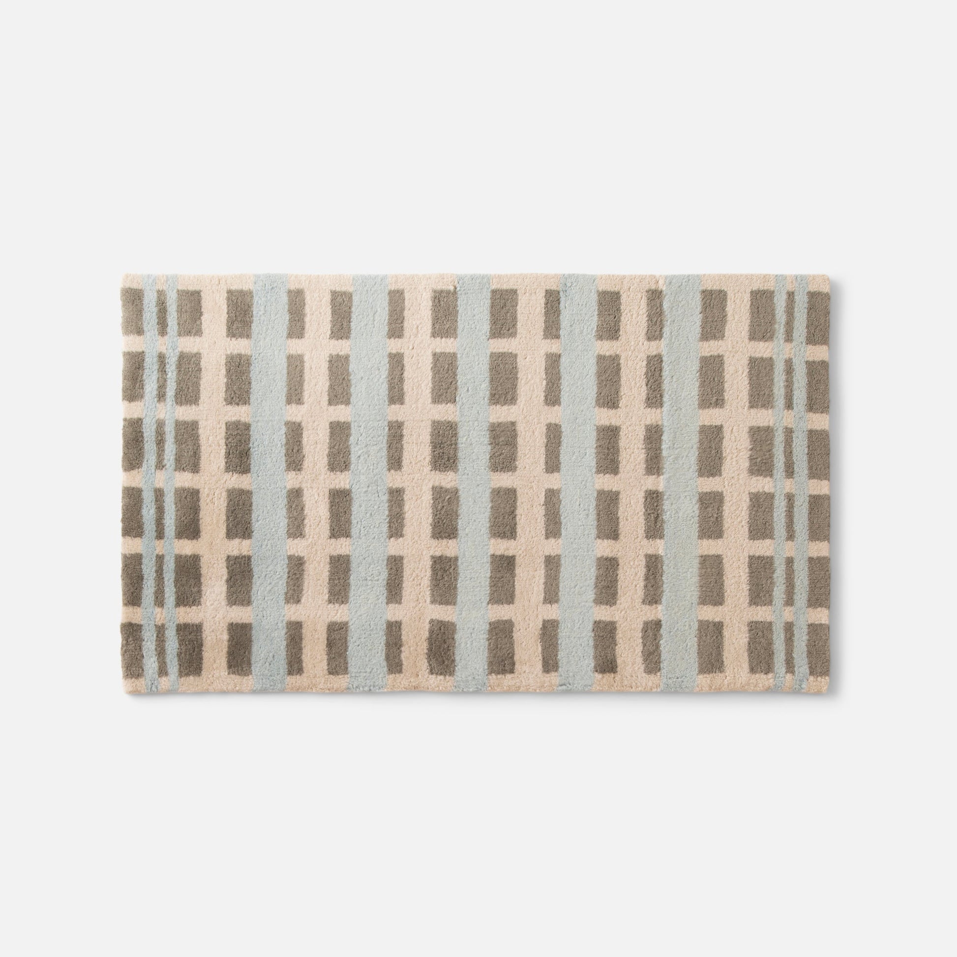 Flat lay of Network Tufted Wool Rug showcasing high pile geometric pattern in blue and taupe on white background