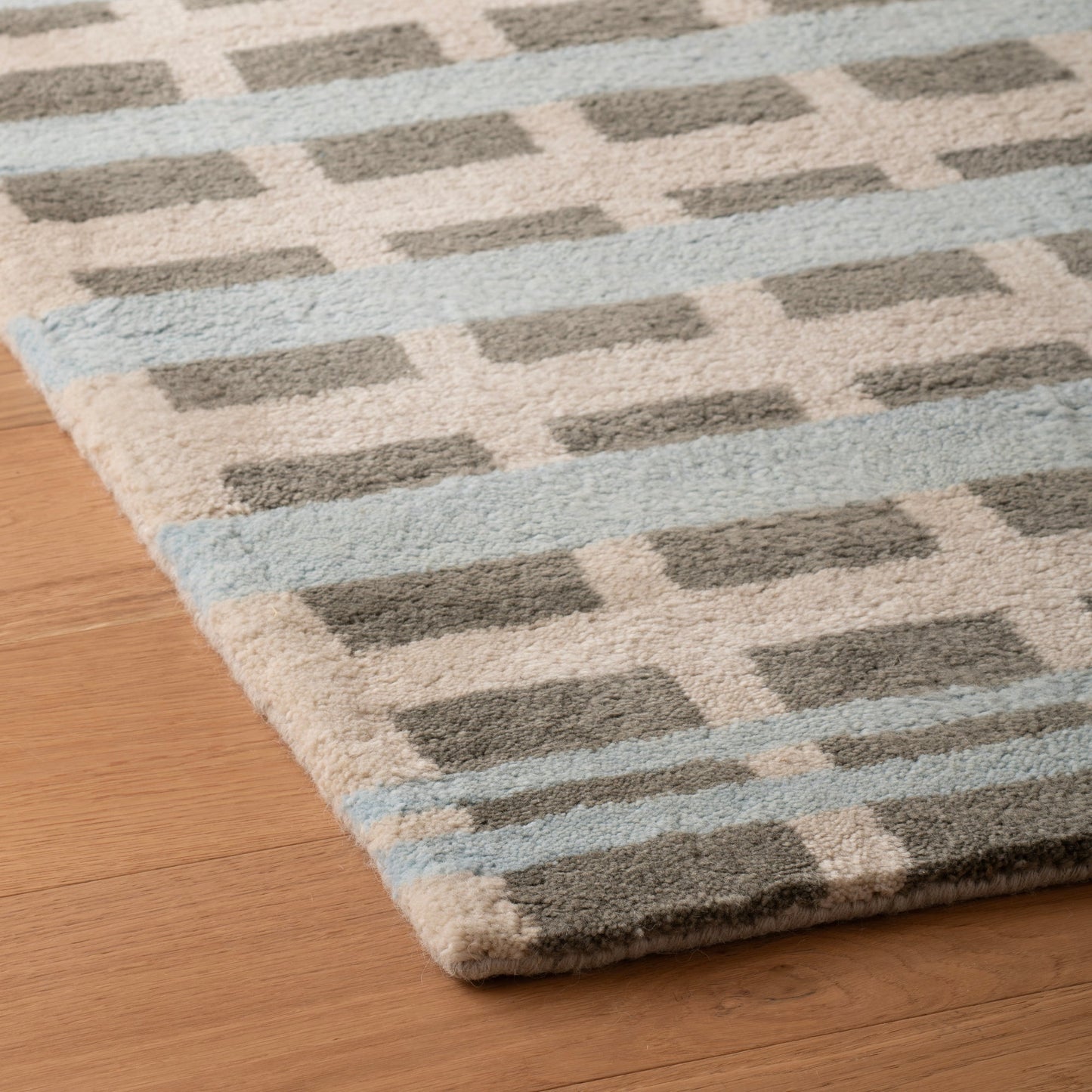 Close up of Network Tufted Wool Rug showing tufted geometric pattern, high pile plush wool texture on hardwood floor