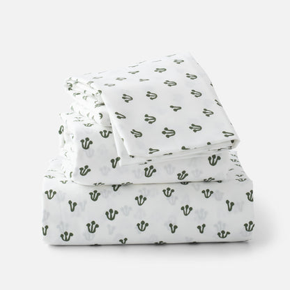 Stacked folded Thistle Percale sheet set showcasing hand-drawn alder green thistle pattern on white background