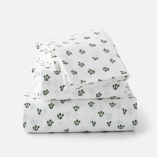 Stacked folded Thistle Percale sheet set showcasing hand-drawn alder green thistle pattern on white background