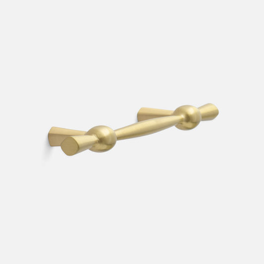 Angled view of Eleanor Pull showcasing curved solid brass bow tie design with a light background