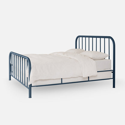 Three-quarter view of Hamilton Bed in blue metal showcasing rounded spindled headboard and footboard with white bedding on light gray background