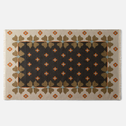 Top edge of Flora Wool Flatweave Rug showcasing geometric folk floral pattern, fringed edge, and dark center