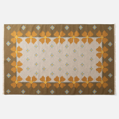 Top-down view of Flora Wool Flatweave Rug showing mustard floral border and small blue-and-yellow motifs on ivory field